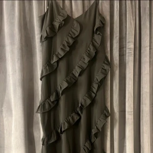 Svart klänning med volanger från Boohoo - Snygg svart klänning från Boohoo med volangdetaljer som ger en trendig look. Klänningen har en dragkedja i ryggen för enkel påklädning. Perfekt för en stilfull kväll. Säljer då den tyvärr aldrig kom till användning.