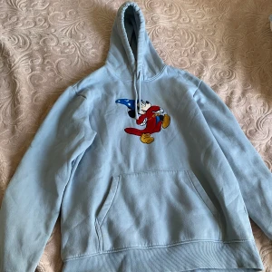 Ljusblå hoodie med Disney-motiv - Säljer en ljusblå hoodie från Disney , Hoodien har en rymlig ficka framtill och en bekväm huva. Perfekt för alla Disney-fans! 🐭✨