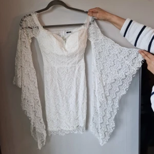 Vit spetsklänning med vida ärmar - Elegant vit klänning i spets med vida, långa ärmar. Perfekt för studenten. Säljer fler klänningar så kika gärna på min profil.