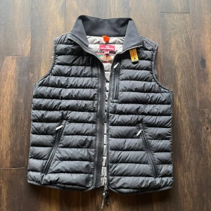 Svart dunväst från Parajumper - Säljer en svart dunväst från Parajumper med dragkedja och praktiska fickor. Västen har en säkerhetsficka på insidan och är perfekt för kyligare dagar. Den quiltade designen ger en stilren look. Finns dock deffekter som syns på bild tre samt 4, knappt så att man lägger märke till dem. Priset är ej hugget i sten.