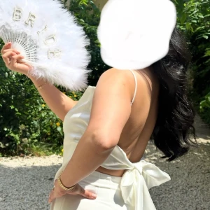 Vit topp från Zara - Säljer en elegant vit satin topp från Zara med smala axelband och en stor rosett i ryggen. Toppen har en öppen rygg. Använd en gång, nyskick Storlek M