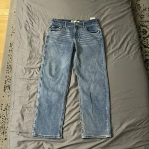 Blå jeans från Levi's - Säljer ett par snygga blå jeans från Levi's med en loose taper passform. De har klassisk femficksdesign och en knappgylf. Perfekta för en avslappnad stil.