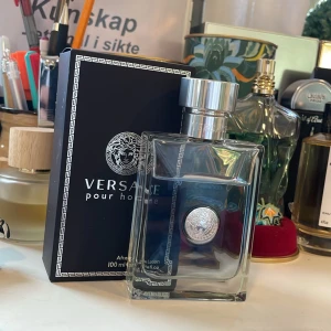 Versace Pour Homme After Shave Lotion 100ml - Säljer en elegant Versace Pour Homme After Shave Lotion i en stilren glasflaska med silverfärgad kork och Versaces ikoniska medusamotiv. Flaskan rymmer 100 ml och kommer i en snygg svart kartong med grekiskt mönster. Perfekt för den stilmedvetne mannen.