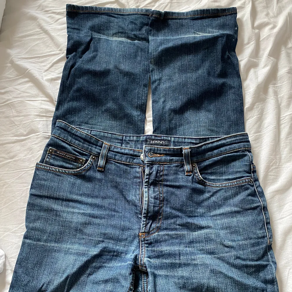 Snygga blå jeansbyxor från Gant med klassisk femficksdesign och en brun läderpatch baktill. Byxorna har en bootcut passform. Storlek W30/L34. Farkut & Housut.