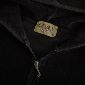 Hoodie - Juicy Couture - Säljer min svarta hoodie från Juicy Couture med dragkedja och huva. Den klassiska 2000-tals hoodien, med tajt och croppad passform. Köpt i USA. Säljs då den är lite liten på mig. Storlek M men motsvarar nog mer en S!💓 (samma tröja som på sista bilden, bara att den jag säljer är svart) 