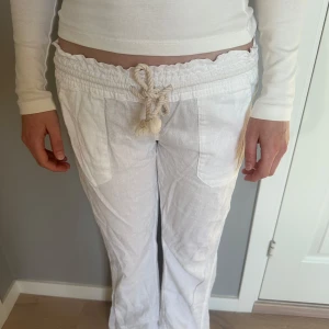 Vita linnebyxor med snörning - Säljer ett par vita linnebyxor med snörning i midjan. Märke Roxy.