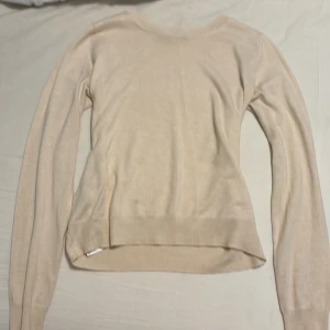 Beige långärmad tröja - Säljer en stilren beige långärmad tröja med rund hals. Perfekt för en avslappnad look. Tröjan har ribbade muddar vid ärmslut och nederkant.