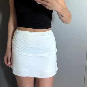 vit minikjol - Säljer en vit minikjol med insydda shorts. Kjolen är använd några enstaka gånger men har inga defekter!
