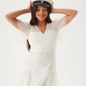 Studentklänning, Vit spetsklänning med v-ringning - Säljer en söt vit klänning med v-ringning och spetsdetaljer. Klänningen har korta ärmar och en volangkjol. Perfekt för studenten! Köpt för 800kr från bubbelroom. Helt oanvänd med prislappen kvar.