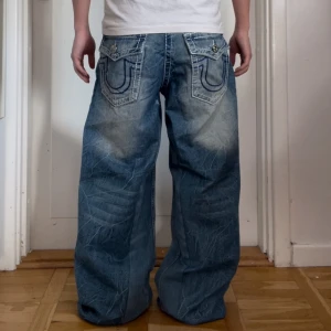 Baggy true religion jeans - Jätte snygga true religion jeans med unika broderade detaljer på bakfickorna. Sömmarna är vit och blå med inga sakador. Jeansen är i storlek M