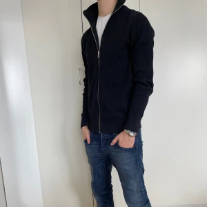 Svart ribbad kofta med dragkedja (HELT NY) - Pris kan diskuteras! .         Perfekt för lager-på-lager och har en stilren look. Passar bra till jeans eller chinos för en avslappnad stil. Skicka 10/10. Modellen är 173