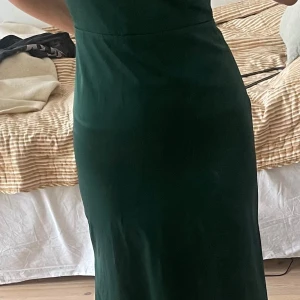 Grön långklänning i satin - Elegant grön långklänning i satin med en vacker rosettdetalj vid halsen💞. Skriv för mått och mer info!Klänningen har en smickrande passform och är perfekt för speciella tillfällen. Den glänsande ytan ger en lyxig känsla.