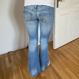 Lågmidjade bootcut jeans med snygga fickor - Snygga blå bootcut jeans med broderade detaljer på bakfickorna. De är lowwaist! Köpte på vinted men var tyvärr för korta på mig som är 171 (min syrra på bild 1 är ca 163) Verkligen super snygga!!!😻Skriv för mått eller fler bilder! Storlek 0 som motsvarar XS💖