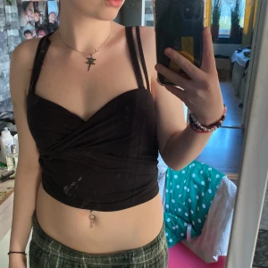 Svart omlottlinne - Säljer ett svart omlottlinne med smala axelband. Toppen är croppad och har en stilren design som passar perfekt för varma dagar.