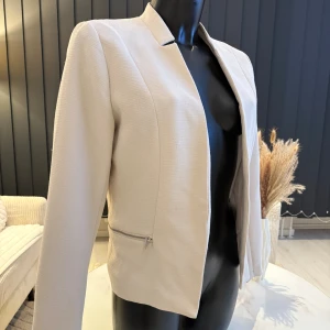 Beige kavaj med dragkedja - Snygg beige kavaj med dragkedja framtill. Den har en stilren design med långärmade ärmar och en normal passform. Perfekt för att ge en elegant touch till din outfit. Passar perfekt som oversize modell.👌🌸