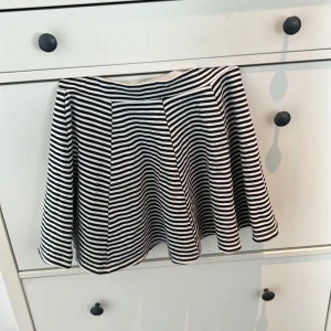 Randig kjol - Snygg kortkjol med svartvita ränder. Kjolen har en vid passform och är perfekt för en stilren look. Den är gjord i ett mjukt material som ger en bekväm känsla hela dagen.