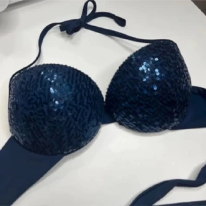 Mörkblå bikini med paljetter - Snygg mörkblå bikini från Calzedonia med glittrande paljetter på kuporna. Bikinin har knytband runt nacken och ryggen för justerbar passform. Perfekt för en dag på stranden eller vid poolen.