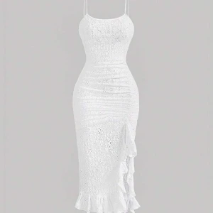 Vit spetsklänning med volangdetaljer - Helt ny, Elegant vit klänning i spets med smala axelband och volangdetaljer längs sidan. Den har en tight passform som framhäver figuren och en vacker volangkant vid fållen. Perfekt för sommarens festligheter.