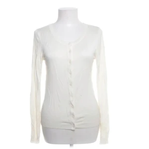 Vit kofta med fjärilsdetalj - Säljer en elegant vit kofta med knappar framtill och en vacker fjärilsdetalj i silver på ryggen. Perfekt för att lägga till en touch av stil till din outfit. Långärmad och i ett mjukt material.