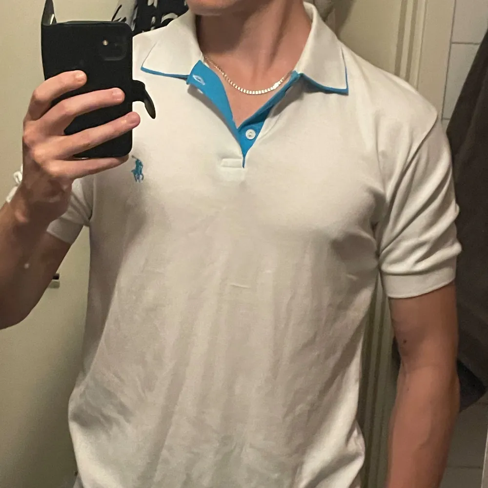 En vit Polo Ralph Lauren pikétröja med blå design på kragen | Storlek XL | Mycket fint skick 👍    Modellen är 182cm lång, väger 75kg  Kolla in min profil för fler pikétröjor, skjortor och annat till bra pris! Fler varor kommer inom kort 💸. T-shirts.