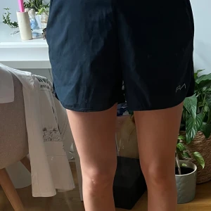 Löparshorts från NA - Blåa Löparshorts från NA med orangea undershorts. Shortsen har mobilficka och snören i midjan 