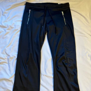 Lågmidjade svarta byxor - Lågmidjade (mjukis?) byxor från Madonna x H&M med slits med dragkedja. Fickorna är riktiga. Finns ett litet hål i byxorna men syns inte