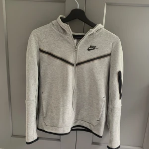 Nike Tech grå - Tjena! Säljer nu min gamla Nike tech då den är för liten och inte min stil. Den passar om du är 155 till 162cm då det är storlek L i barn. Skicket är 8/10. Nypris är 1100kr och mitt pris är 550. hör av er om ni ha några frågor köparen står för frakt 