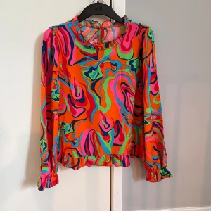 Ny oanvänd färgglad blus i stl S - Ny oanvänd färgglad blus. Blusen är i stl S. Den köptes för en temafest ’Färgglatt’, men då jag inte kunde närvara användes den aldrig. 