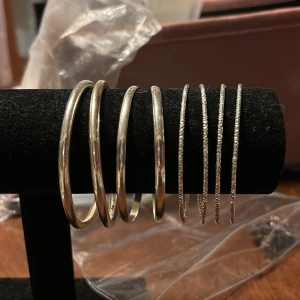 Set med silverfärgade armband - Ett set med åtta silverfärgade armband. Setet innehåller både släta och glittriga armband. Perfekt för både vardag och fest. Kan va någon liten repa men annars i braskick 