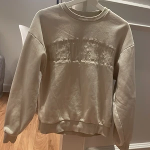 Tjocktröja - En beige tjock tröja med text 