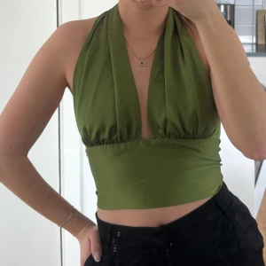 Grön topp - Grön topp med öppen rygg. Man knyter i nacken och i ryggen, så den är väldigt justerbar i storleken. Har klippt bort storlekslappen men sitter som en 36 / S