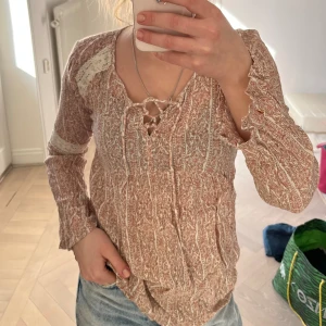 Blus - En blus med spets och vida ärmar, den har knytning i fram och superfint mönster 