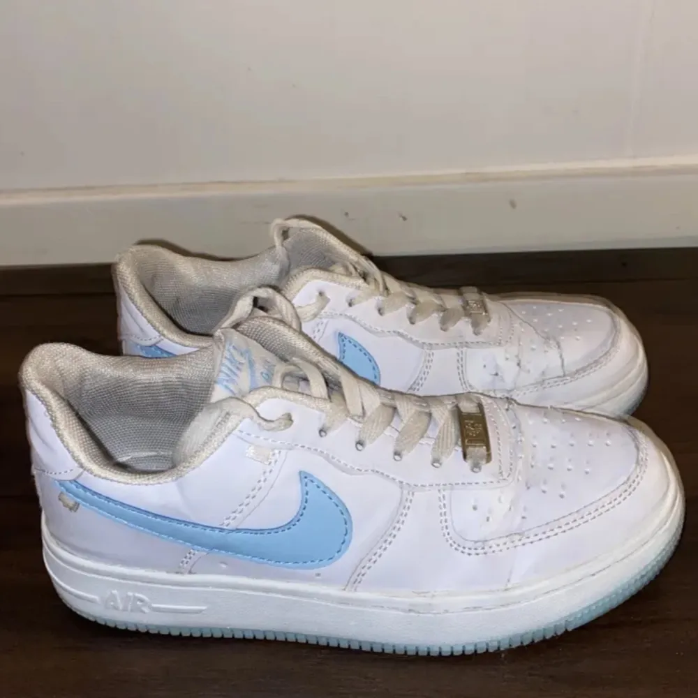 Vita Nike air force 1 sneakers med ljusblå logga och sula! Använda men i bra skick, storlek 39 Nypris 1600:-. Skor.