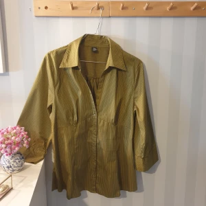 Skjorta  - olivgrön skjorta med lite figur passform och i strech från H&M. Står storlek 46 men skulle säga mer som en 42/44