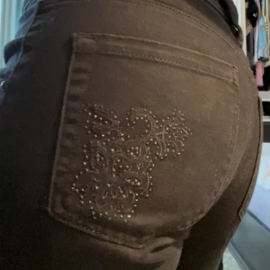 Y2K jeans bakficka detalj stl M - Ett par svarta jeans från Lindex med rhinestone detaljer på bakfickan.   Storlek 40/stor medium  De är straight fit men ser lite flared ut på. Jag är 171 cm lång. Skicka gärna meddelande vid frågor! Tack för titten!