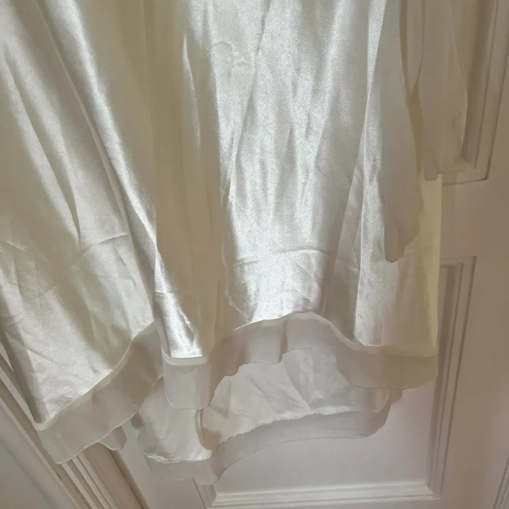 En till vit klänning i gräddvit med band runt midjan, dold dragkedja och öppen rygg. Använd en gång men det finns en liten smuts enligt bilden som går bort i tvätt. Jag har aldrig tvättat den.. Klänningar.
