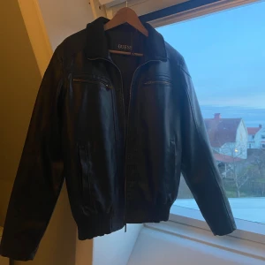 Skinnjacka Guess - Fin skinnjacka i mycket bra skick från Guess. Den är svart/mörkbrun i färgen och sitter overzised på mig som vanligtvis har st XS-S. Den är fodrad sp funkar både till kallare perioder och till våren:) Säljer pga kommer inte till användning. 