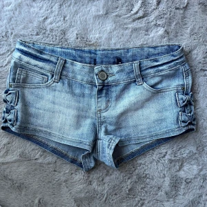 Lågmidjade jeansshorts - Säljer dessa jätte söta lågmidjade jeans shorts i perfekt skick!🤩 det är jättegulliga rosetter på sidan av shortsen. Stl 38 men shortsen är lite små i storleken så mer en 36