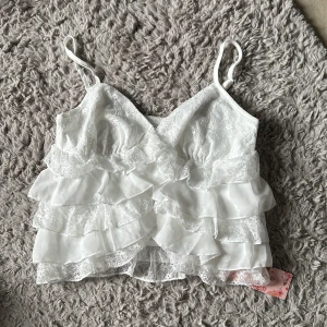 Sommar blus - Hej! Jag säljer min helt nya sommartopp. Den är vit med volanger med små knappar där fram som inte syns så mycket. 