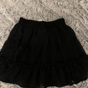 Svart kjol - Super söt volangkjol sitter jätte skönt i midjan då den är elastisk! Inte genomskinlig!