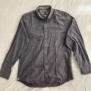 Tommy Hilfiger Skjorta - Grå Tommy Hilfiger Slim Fit skjorta i använt skick. Skjortan är något blekt men i stort är plagget bra, fler bilder skickas på förfrågan 🔥 Skriv vid funderingar! Prisförslag välkomnas FLER LIKNANDE PLAGG PÅ PROFILEN 86