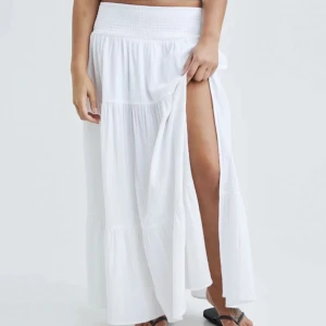 Lång kjol med slit - Lång vit kjol med slit från bik bok. Går ej att köpa längre, knappt använd. Jätte fin till sommaren💗