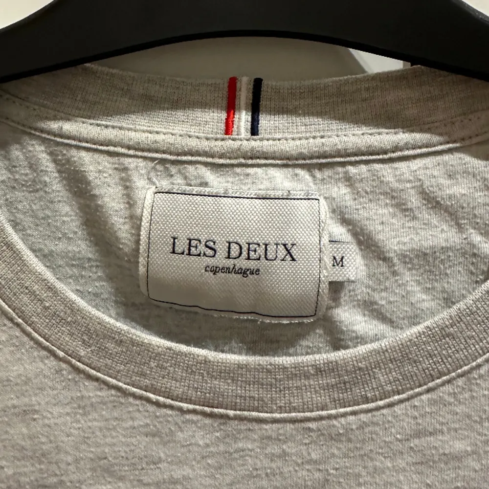 Säljer en grå t-shirt från Les Deux med slapp passform. Stilren med ett litet märke på vänster sida i höjd med bröstkorgen. Ganska oanvänd och i bra skick.. T-shirts.