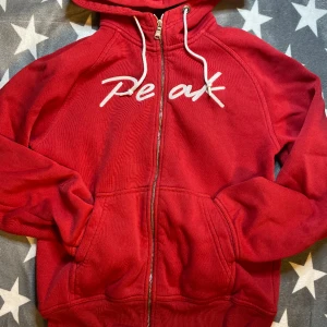Röd zip up Peak hoodie  - En väldigt liten fläck på högra fickan som man knappast ser men annars bra skick. Hoodien finns ej att köpa i butiker osv längre. 
