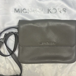 Michael Kors väska  - Superfin väska från Michael Kors i grått med flera fack varav ett med dragkedja. Höjd 17 bredd 22