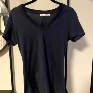 T-shirt från Acne Studios med V-ringning i en marinblå färg. Använd endast ett fåtal gånger. Säljorsak: för liten. 