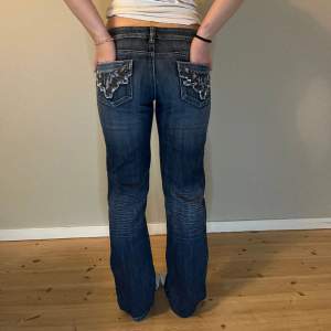 Mörkblå lågmidjade jeans med snygga detaljer på bakfickorna 😻   Mått: Midjemått- 36 cm Innerbenslängd- 79,5 cm Ytterbenslängd- 102 cm