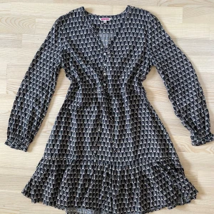 Klänning med volang från Indiska - Stl 36, normal i storleken Från Indiska Dragsko i midjan och volanger nedtill Små söta knappar upptill i pärlemo Går strax ovanför knät på mig som är 174cm Hittar inget att anmärka på