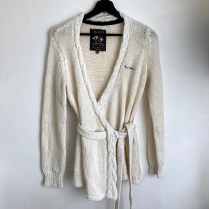 Naturvit kofta, Bondelid, stl. S, bohemisk, boho, ull, alpacka, cardigan, omlott - Naturvit omlott-kofta från Bondelid. Guldfärgad glittertråd i kragen, muddarna och i knytbandet. Lätt slitage i form utav noppor. Mått får ej plats - fråga gärna!