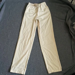 Tygbyxor  - Helt nya tygbyxor i fin beige färg, väldigt bra kvalitet, fickor på sidan och dragsko i insidan vid midjan.  Innreben: 77cm Yttreben: 106,5cm